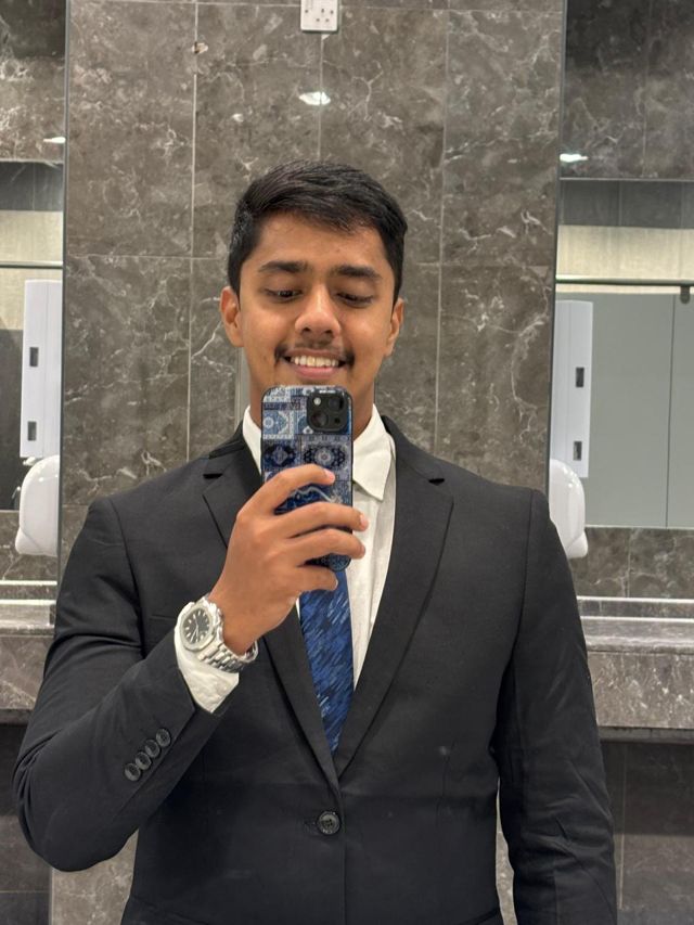 Mirror photo of Usman in a black suit and blue tie